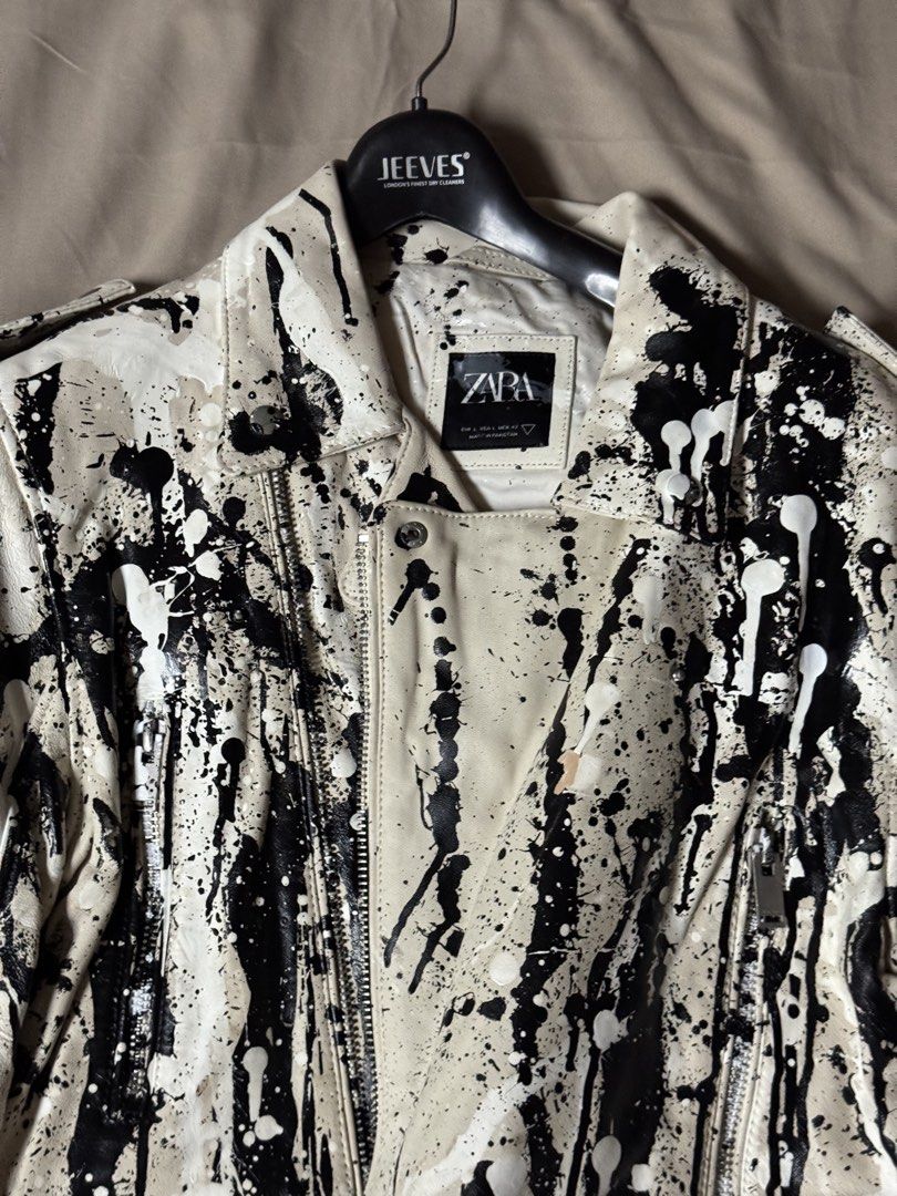Zara Paint Splatter Faux Leather Biker Jacket (Category: Coats, Jackets and Outerwear) located in Manila. Submitted by seangoart (Listing ID 1465511259, Image 2). Description: White faux leather biker jacket from Zara. Covered in black and white paint splatter design all over. Asymmetrical front zipper, zipped pockets, and lapel collar. Size L. Made in Pakistan. Statement piece with an edgy street style look. Heavy paint drip details across the f