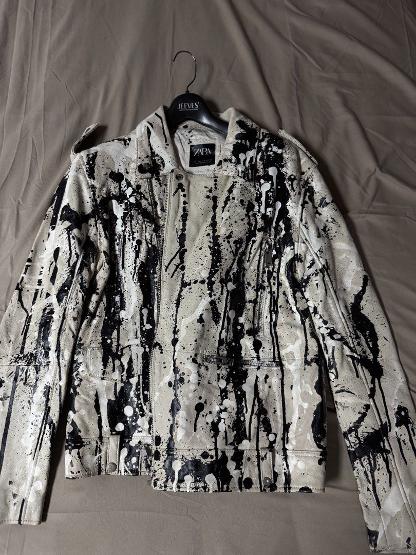 Zara Paint Splatter Faux Leather Biker Jacket (Category: Coats, Jackets and Outerwear) located in Manila. Submitted by seangoart (Listing ID 1465511259, Image 1). Description: White faux leather biker jacket from Zara. Covered in black and white paint splatter design all over. Asymmetrical front zipper, zipped pockets, and lapel collar. Size L. Made in Pakistan. Statement piece with an edgy street style look. Heavy paint drip details across the f