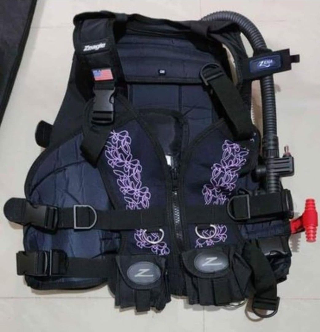 Zeagle Zena BCD with extra Front Panels and Storage Bag (Category: Water Sports) located in Binan City. Submitted by rft5523267 (Listing ID 1465489517, Image 2). Description: - Brand: Zeagle - Color: Black and purple - Material: Heavy-duty nylon (Made in USA) - Included: Main BCD vest, integrated weight pockets, inflator hose, separate purple/black harness vest, and original storage bag - Features: Fully adjustable straps and quick-release buckle