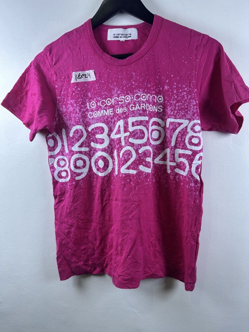 10 Corso Como Comme des Garcons Pink Number Graphic Tee (Category: Shirts) located in Manila. Submitted by declutterpromax (Listing ID 1469214617, Image 1). Description: - Brand: 10 Corso Como x Comme des Garcons - Color: Pink with white graphic print - Size: Small (Measures approx. 18" chest, 24" length) - Material: 100% cotton, Made in Japan - Details: Model code SB-T907, AD2008 release - Care: Hand wash only.