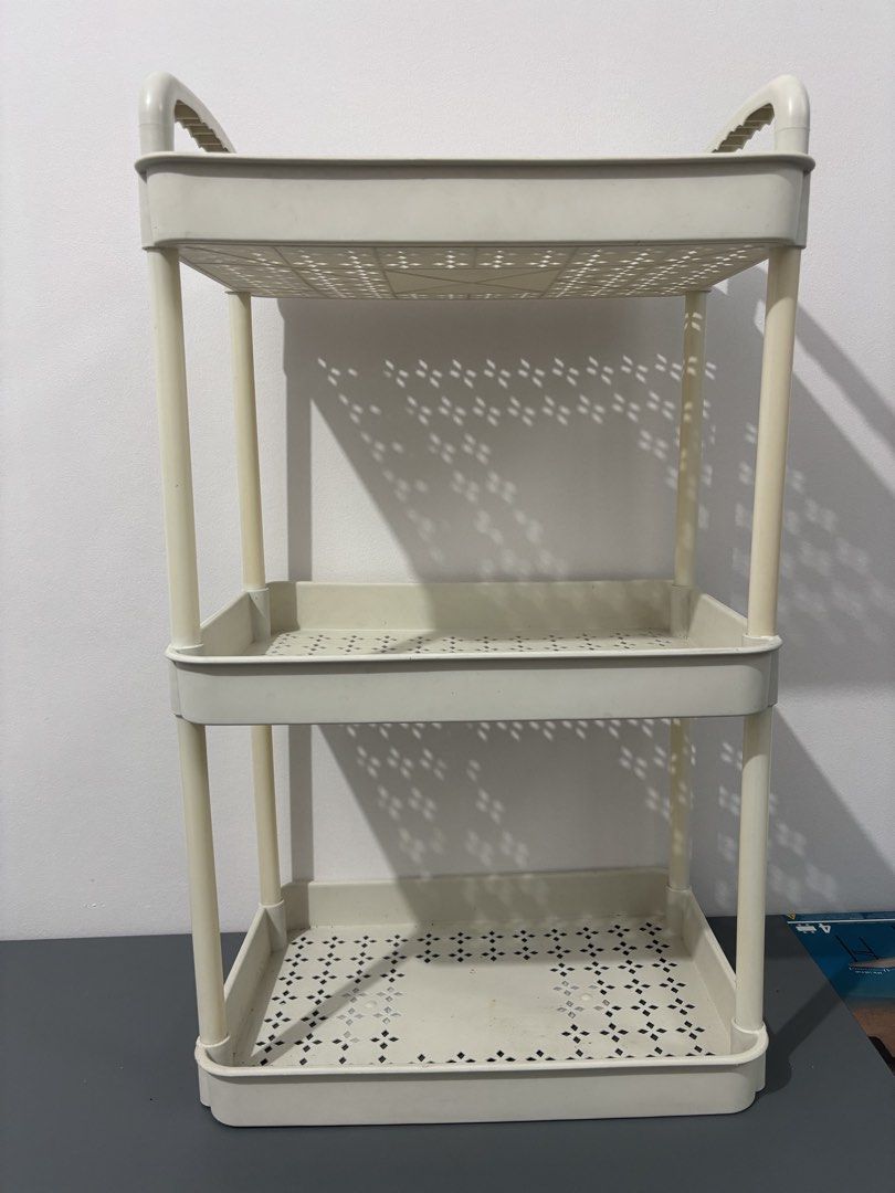 3-tier plastic utility storage rack with handles (Category: Storage Boxes & Baskets) located in Manila. Submitted by safefire.ae92b7 (Listing ID 1469357889, Image 2). Description: - Color/Material: Beige plastic - Tiers: 3 shelves with open design and geometric cut-out patterns - Mobility: Built-in top handles for easy pulling and moving - Type: Lightweight, freestanding organizer unit - Best for: Extra storage in bathrooms, kitchens, and laundry