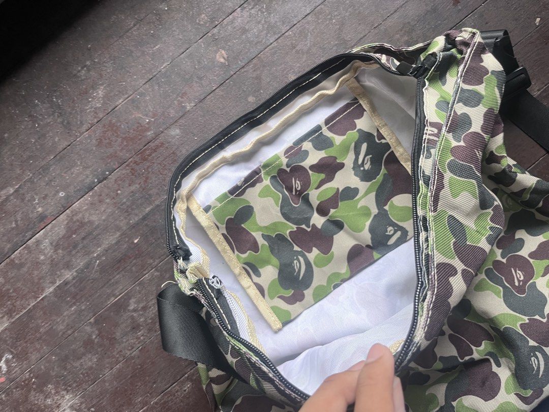 A Bathing Ape BAPE Camo Messenger Bag (Category: Sling Bags) located in Kalibo. Submitted by mattpogi15 (Listing ID 1469181806, Image 2). Description: - Iconic green and brown BAPE camo design - Durable canvas material with an adjustable black shoulder strap - Spacious main compartment with a secure zippered closure - Features a matching camo inner slip pocket and clean white lining - Perfect size for daily commute, school, or casual streetwear s