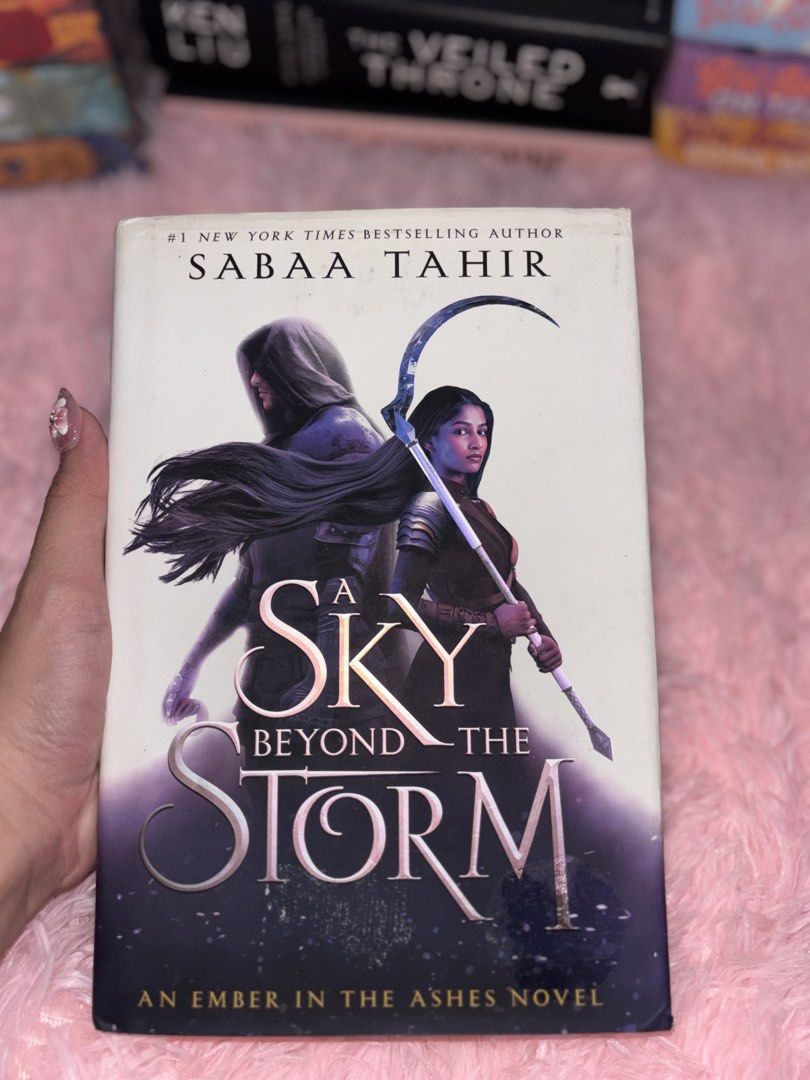 A Sky Beyond the Storm by Sabaa Tahir (Category: Storybooks) located in Batangas. Submitted by solunarareads (Listing ID 1469202772, Image 1). Description: - Title: A Sky Beyond the Storm by Sabaa Tahir - Series: Book 3 of An Ember in the Ashes quartet - Format: Hardcover with dust jacket - Condition: Minor shelf wear on dust jacket edges; yellowing and spotting on page edges - Note: Red remainder dot stamped on the bottom page block - Perfect fo