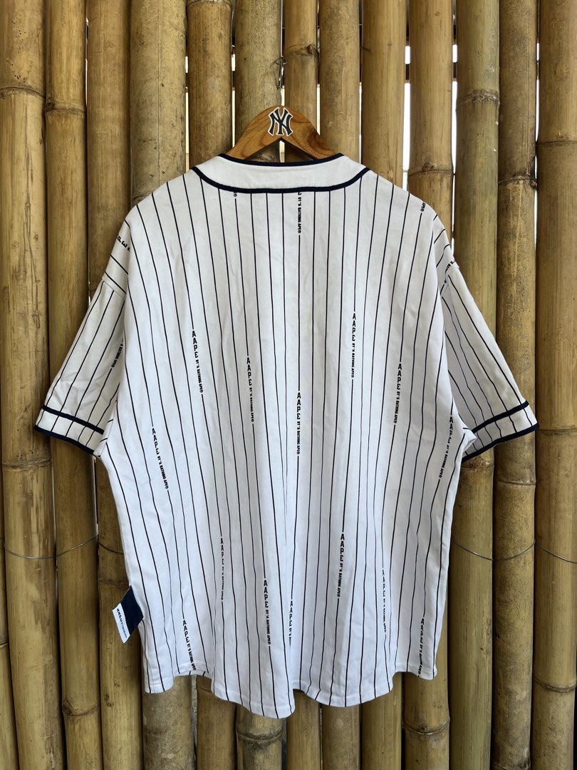 Aape By A Bathing Ape Pinstripe Baseball Jersey (Category: Tshirts & Polo Shirts ) located in Manila. Submitted by thrifttika (Listing ID 1469222530, Image 3). Description: - Brand: Aape by A Bathing Ape - Style: White baseball jersey with navy blue pinstripes - Details: Large raised AAPE chest lettering, button-down front with branded buttons, and woven lower front patch - Size: Large - Condition: Clean, flawless and ready to wear.