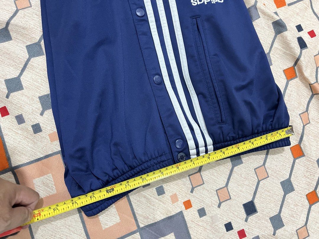 Adidas Blue Button-Up Track Pants Size M (Category: Joggers) located in Adams. Submitted by m1k3yl (Listing ID 1469215984, Image 2). Description: - Brand: Adidas - Color: Navy blue with white side stripes - Size: Medium - Features: Full button snaps along outer legs, elastic waistband with adjustable drawstring, and two side pockets - Origin: Made in Indonesia - Condition/Use: Great for sports, workouts, or everyday chilling.