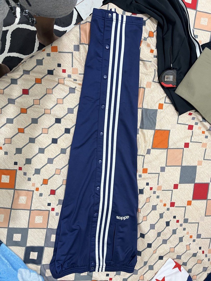 Adidas Blue Button-Up Track Pants Size M (Category: Joggers) located in Adams. Submitted by m1k3yl (Listing ID 1469215984, Image 3). Description: - Brand: Adidas - Color: Navy blue with white side stripes - Size: Medium - Features: Full button snaps along outer legs, elastic waistband with adjustable drawstring, and two side pockets - Origin: Made in Indonesia - Condition/Use: Great for sports, workouts, or everyday chilling.