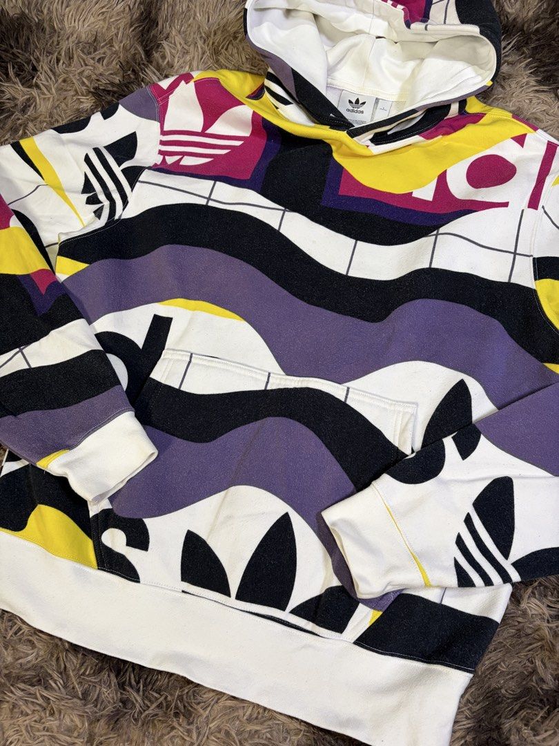 Adidas Catalog AOP Hoodie Multicolor Size S (Category: Hoodies) located in Manila. Submitted by _valuevault777 (Listing ID 1469178141, Image 2). Description: - Brand: Adidas - Model: Catalog AOP Hoodie - Size: S - Design: Multi-colored abstract graphic print with white base, black, purple, yellow, magenta, and integrated Trefoil logos - Features: Kangaroo front pocket, adjustable drawstring hood, ribbed cuffs and hem - Material: 77% cotton, 23% r