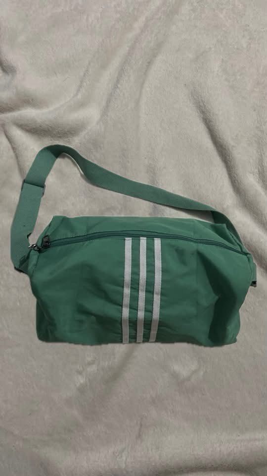 Adidas Green Duffel Bag with White Stripes (Category: Sling Bags) located in Manila. Submitted by nobleowl-8fff (Listing ID 1469290884, Image 1). Description: - Authentic green Adidas duffel bag featuring the classic white three stripes - Spacious main compartment ideal for gym gear, sports equipment, or weekend travel - Secure zippered top closure to keep your belongings safe - Adjustable green shoulder strap for comfortable carrying - Durable a