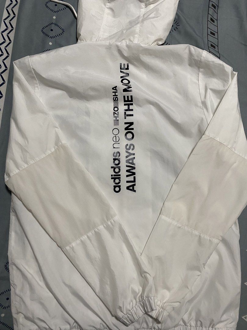 Adidas Neo White Windbreaker Jacket (Category: Coats, Jackets and Outerwear) located in Taguig. Submitted by maaarrrrrcky (Listing ID 1469264185, Image 3). Description: - Brand: Adidas Neo - Color: White with black horizontal chest stripe - Design: Large 'ALWAYS ON THE MOVE' text print on the back - Features: Full zip closure, attached hood with drawstring, functional side pockets - Fit: Elastic cuffs and hem for a snug fit - Size: A/L (180/100A)