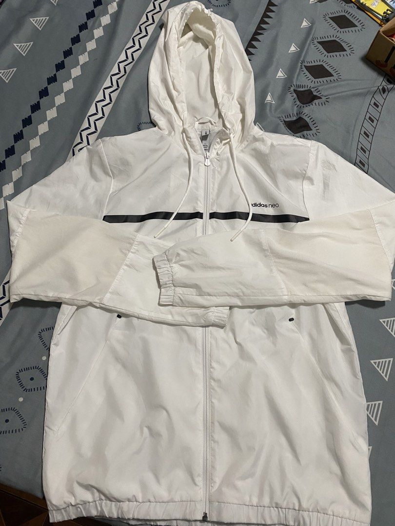 Adidas Neo White Windbreaker Jacket (Category: Coats, Jackets and Outerwear) located in Taguig. Submitted by maaarrrrrcky (Listing ID 1469264185, Image 2). Description: - Brand: Adidas Neo - Color: White with black horizontal chest stripe - Design: Large 'ALWAYS ON THE MOVE' text print on the back - Features: Full zip closure, attached hood with drawstring, functional side pockets - Fit: Elastic cuffs and hem for a snug fit - Size: A/L (180/100A)