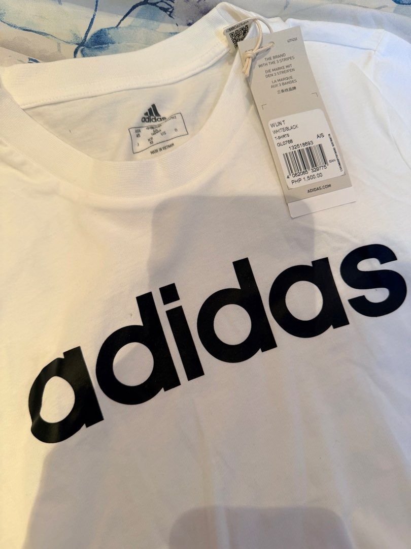 Adidas White Black Linear Logo T-Shirt (Category: Shirts) located in Cebu City. Submitted by cutexoxoshop (Listing ID 1469174724, Image 2). Description: - Brand: Adidas - Condition: Brand new with tags (never worn) - Size: XS - Color: White with large black linear logo on chest - Details: Classic crew neck, short sleeves, small branding on left sleeve - Material: 100% Cotton - Origin: Made in Vietnam - Style: Simple, everyday casual wear.
