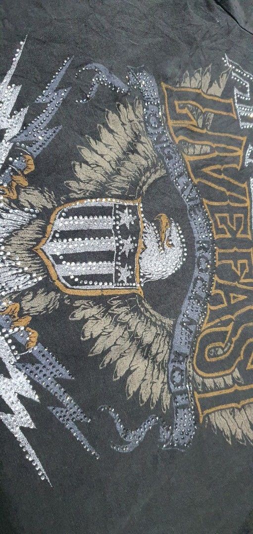 Affliction Live Fast Rhinestone Eagle Graphic T-Shirt (Category: Shirts) located in Laoag. Submitted by floydg_corpuz22 (Listing ID 1469255065, Image 2). Description: Affliction graphic tee with Y2K rocker vibes, featuring rhinestone accents, an eagle shield graphic, and a tie hem. Washed black with distressed details. Affliction for her Xs 17x18 Vgood to excellent need wash 350+sf.