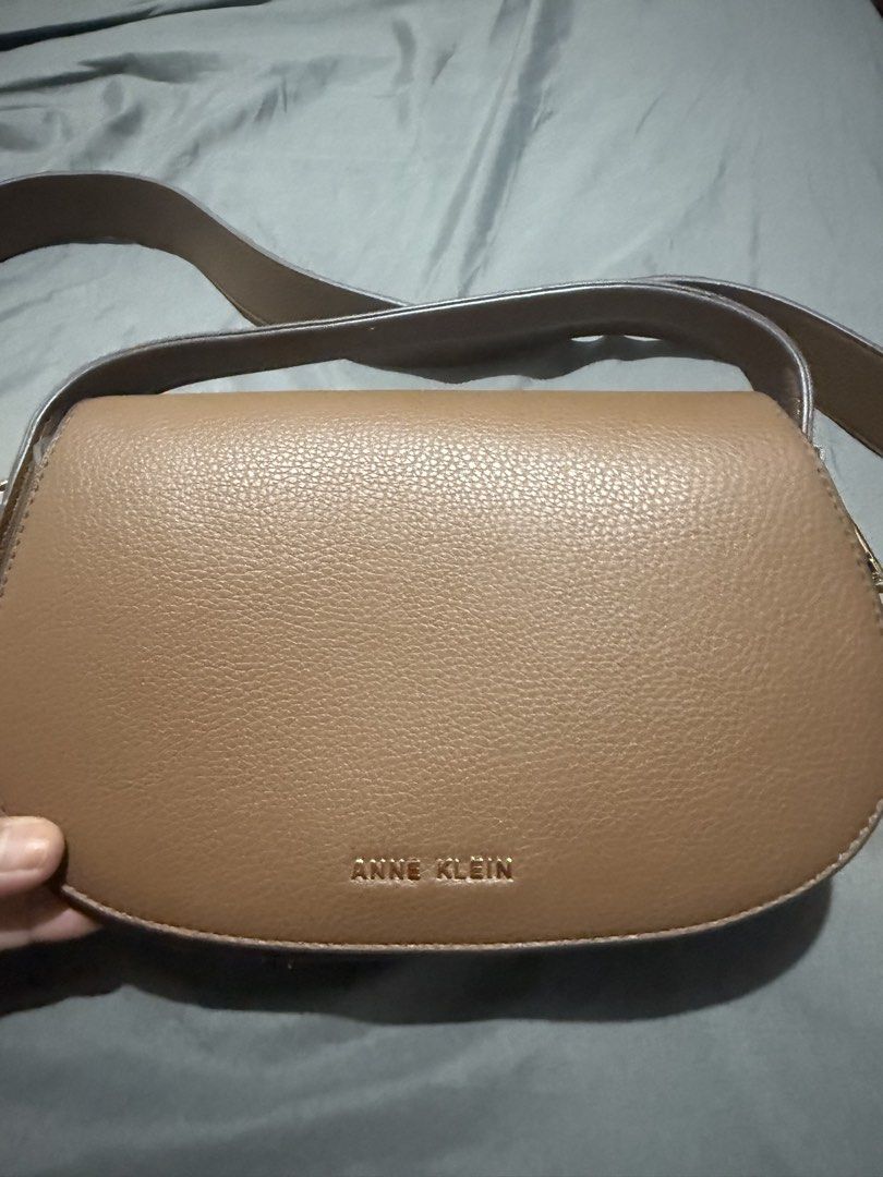 Anne Klein Brown Crossbody Bag with Strap (Category: Cross-body Bags) located in Cainta. Submitted by mykee1 (Listing ID 1469227431, Image 3). Description: - Brand: Anne Klein - Color: Tan brown - Material: Textured faux leather with gold logo lettering - Closure: Front flap - Strap: Matching adjustable shoulder strap with debossed logo - Condition: Clean interior and exterior, ready to wear.