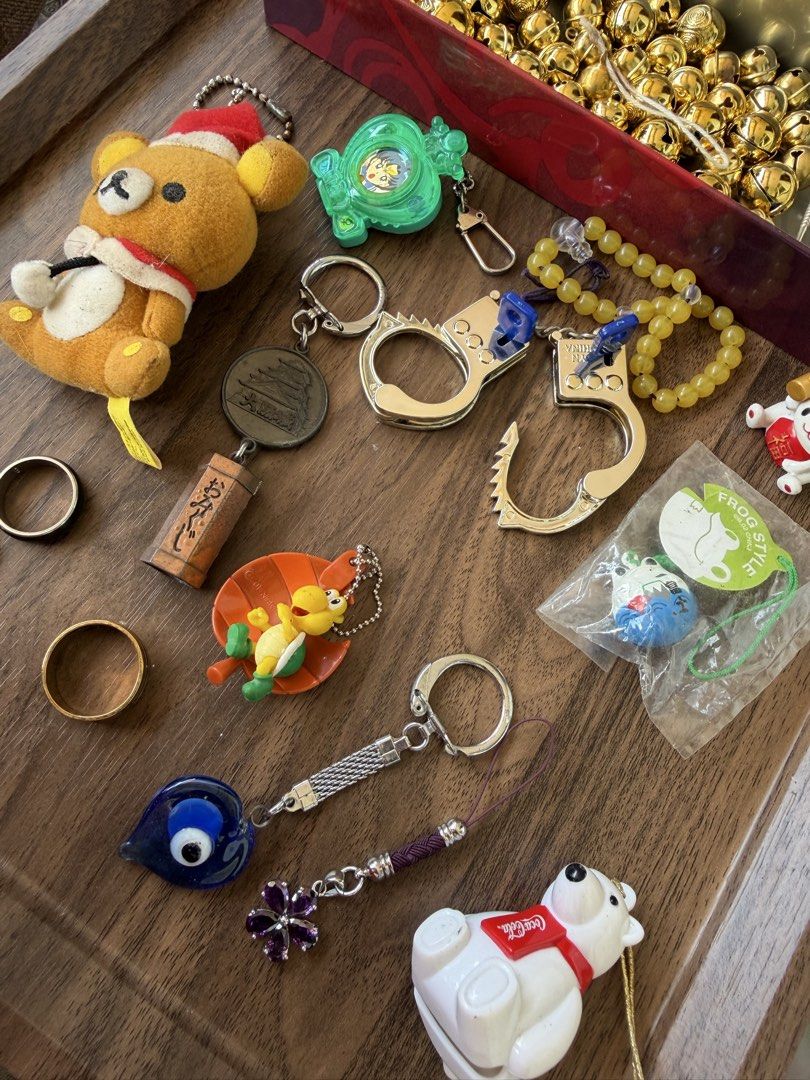 Assorted Keychains and Charms Bundle (Category: Character Goods) located in Digos. Submitted by old_soul. (Listing ID 1469198716, Image 2). Description: - Assorted bundle of random keychains, charms, and trinkets - Featured items: Plush Santa Rilakkuma, miniature handcuffs, Japanese souvenir omikuji charm, evil eye pendant, Coca-Cola polar bear, and small brass bells - Mixed materials including plastic, plush, metal, and glass - Ideal for collect