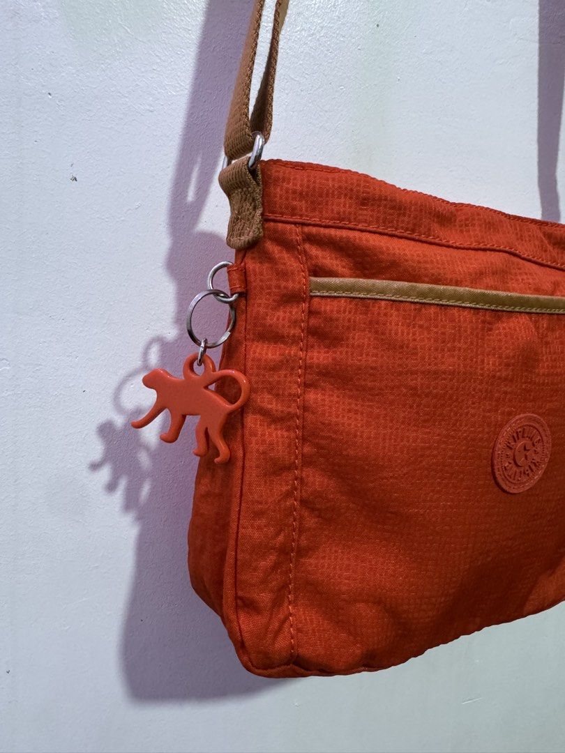 Authentic Kipling Moyelle Crossbody Sling Bag Orange (Category: Cross-body Bags) located in Manila. Submitted by esparciake75752 (Listing ID 1469198898, Image 3). Description: - Brand: Kipling - Model: Moyelle Crossbody Bag - Color: Vibrant Orange with Brown Canvas Strap - Material: Signature crinkled nylon - Compartments: Front slip pocket with piping trim and secure main zip compartment - Details: Iconic circular Kipling logo patch on front - I