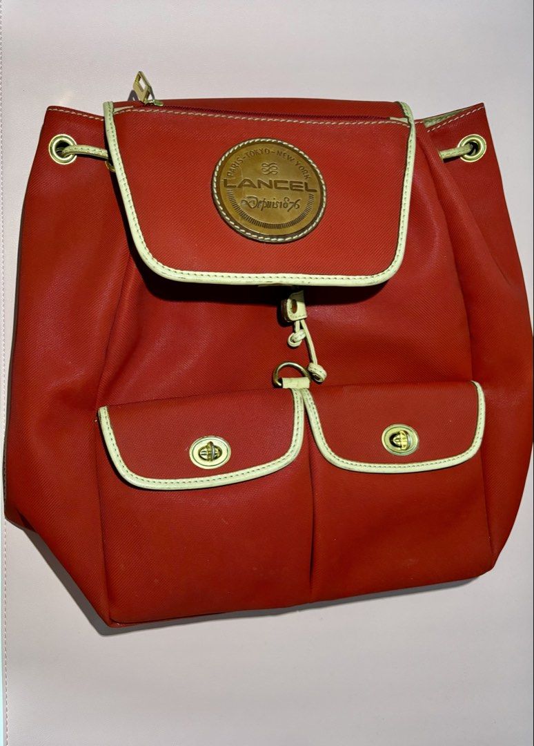 Authentic LANCEL Paris Backpack (Category: Backpacks) located in Pasig City. Submitted by talaversify (Listing ID 1469240761, Image 2). Description: • Authentic Lancel Paris Backpack in bright Red with Tan/Beige Leather Accents • Durable canvas/nylon body material, genuine leather straps and trim in gold-tone hardware fully functional • Secure top flap with buckle latch closure and adjustable drawstring opening • Two prominent front exterior pock