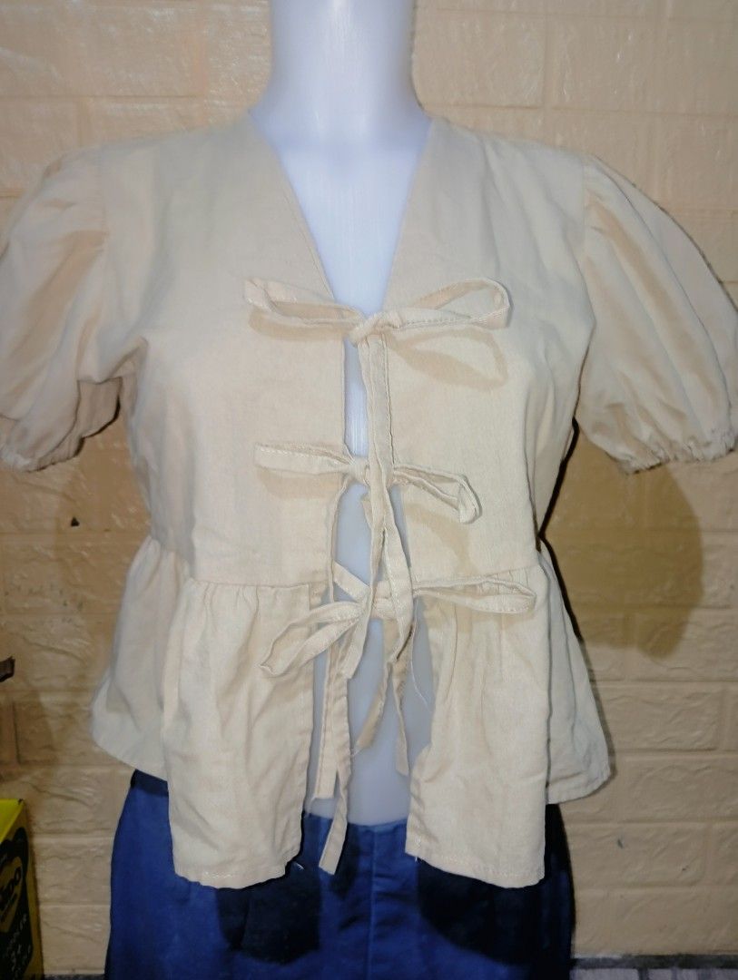 Beige Puff Sleeve Tie Front Blouse (Category: Blouses) located in Manila. Submitted by fatimacorp44140 (Listing ID 1469196899, Image 1). Description: - Color: Beige - Style: Short puff sleeves, front tie closures, peplum hem - Material: Lightweight and very comfortable - Versatility: Easy to match with jeans or skirts for daily casual wear - Condition: Excellent / Like new - Mode of Payment: GCash or BPI - Shipping: Via J&T Express or Lalamove (B