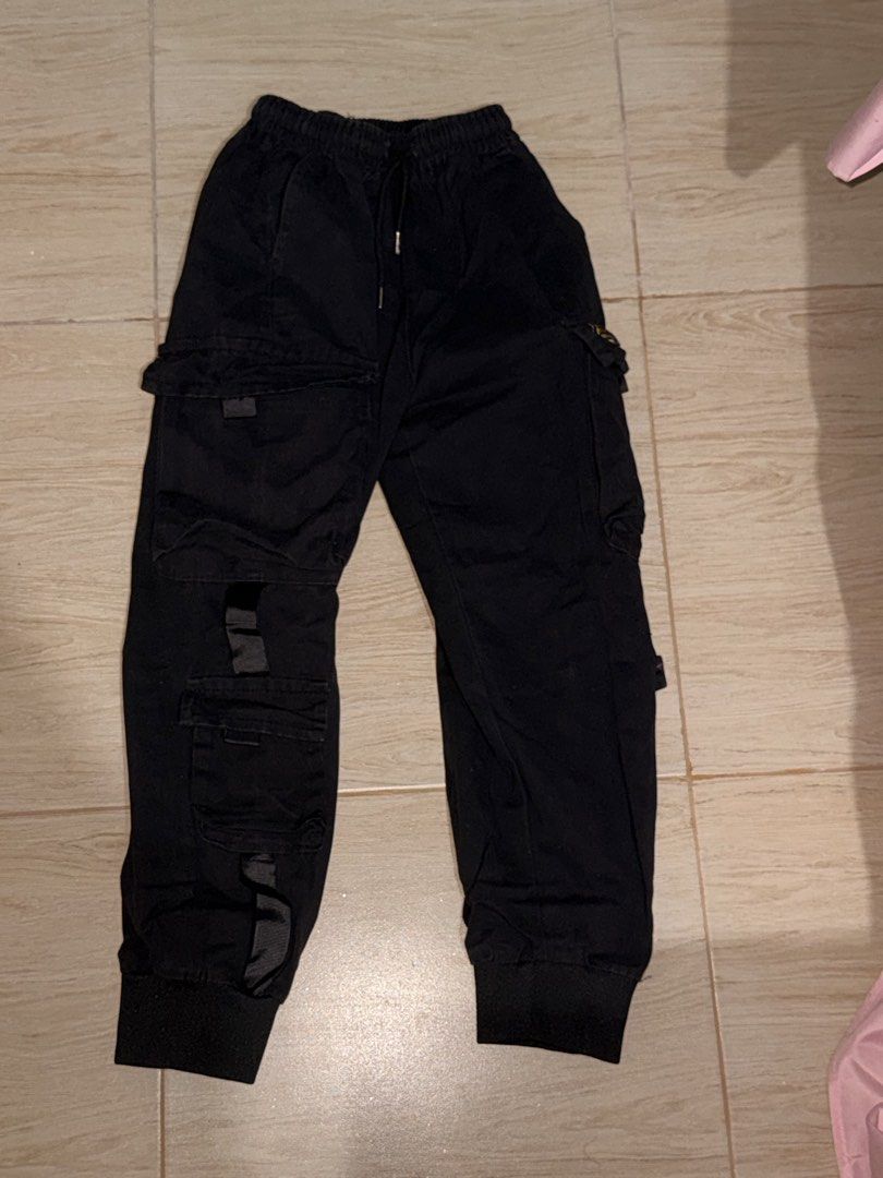 Black Techwear Cargo Joggers with Straps and Pockets (Category: Joggers) located in Solano. Submitted by blkcat1221 (Listing ID 1469257113, Image 3). Description: - Color: Black - Style: Streetwear cargo joggers - Fit: Super comfortable for everyday wear - Waistband: Elastic with adjustable drawstring closure - Cuffs: Ribbed ankle cuffs - Pockets: Multiple utility pockets down the sides - Details: Features decorative straps and a small yellow bra