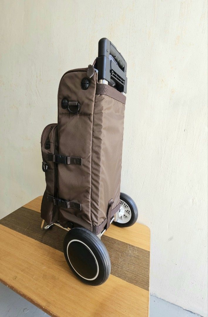 Brown Rolling Trolley Bag with Extendable Handle and Wheels (Category: Luggage) located in Meycauayan. Submitted by amazinggrace_143 (Listing ID 1469291272, Image 2). Description: - Color: Brown - Features: Extendable metal handle, sturdy rolling wheels, and a metal support stand to keep it upright - Storage: Detachable smaller front pouch with zipper, side pockets, and compression straps with buckles - Condition: Clean fabric body, smooth-glidin