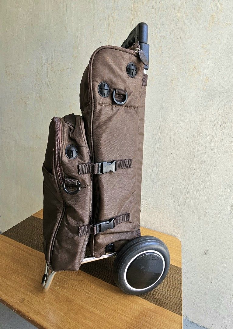 Brown Rolling Trolley Bag with Extendable Handle and Wheels (Category: Luggage) located in Meycauayan. Submitted by amazinggrace_143 (Listing ID 1469291272, Image 1). Description: - Color: Brown - Features: Extendable metal handle, sturdy rolling wheels, and a metal support stand to keep it upright - Storage: Detachable smaller front pouch with zipper, side pockets, and compression straps with buckles - Condition: Clean fabric body, smooth-glidin