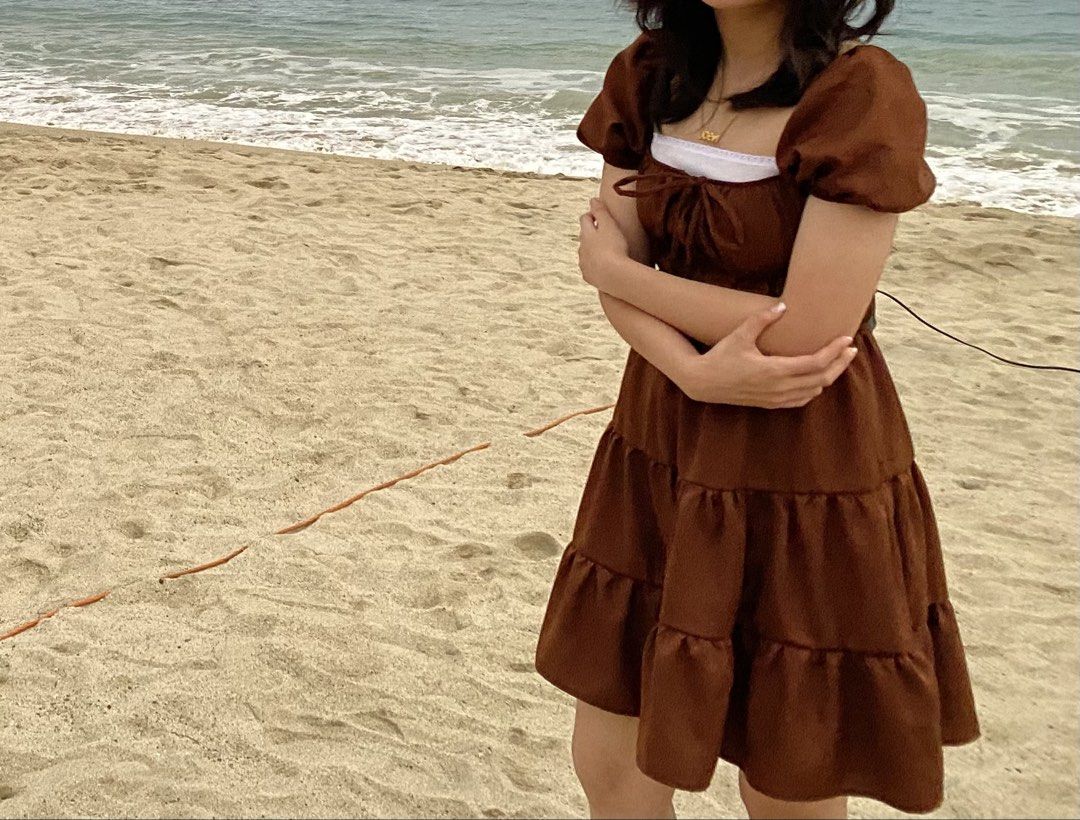 Brown Tiered Puff Sleeve Mini Dress (Category: Dresses) located in Solano. Submitted by blkcat1221 (Listing ID 1469262371, Image 1). Description: - Color: Rich brown with a smooth sheen - Design: Puffy short sleeves, tiered skirt, and ruched bodice with neckline tie - Versatility: Ideal for beach trips or casual day outs - Condition: Worn only once, practically spotless.