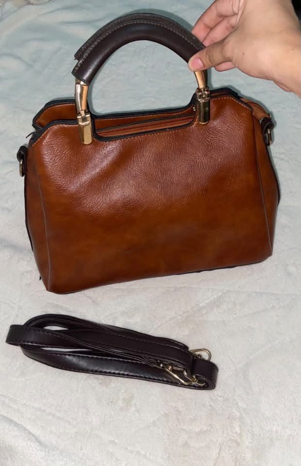 Brown Top-Handle Handbag With Detachable Strap (Category: Shoulder Bags) located in Manila. Submitted by nobleowl-8fff (Listing ID 1469290583, Image 1). Description: - Color & Finish: Rich brown gradient faux leather - Hardware: Elegant gold-tone details - Closure: Secure zippered main compartment - Versatility: Includes a detachable strap for cross-body or hand carry - Condition: Clean interior and exterior with minor storage creases only.