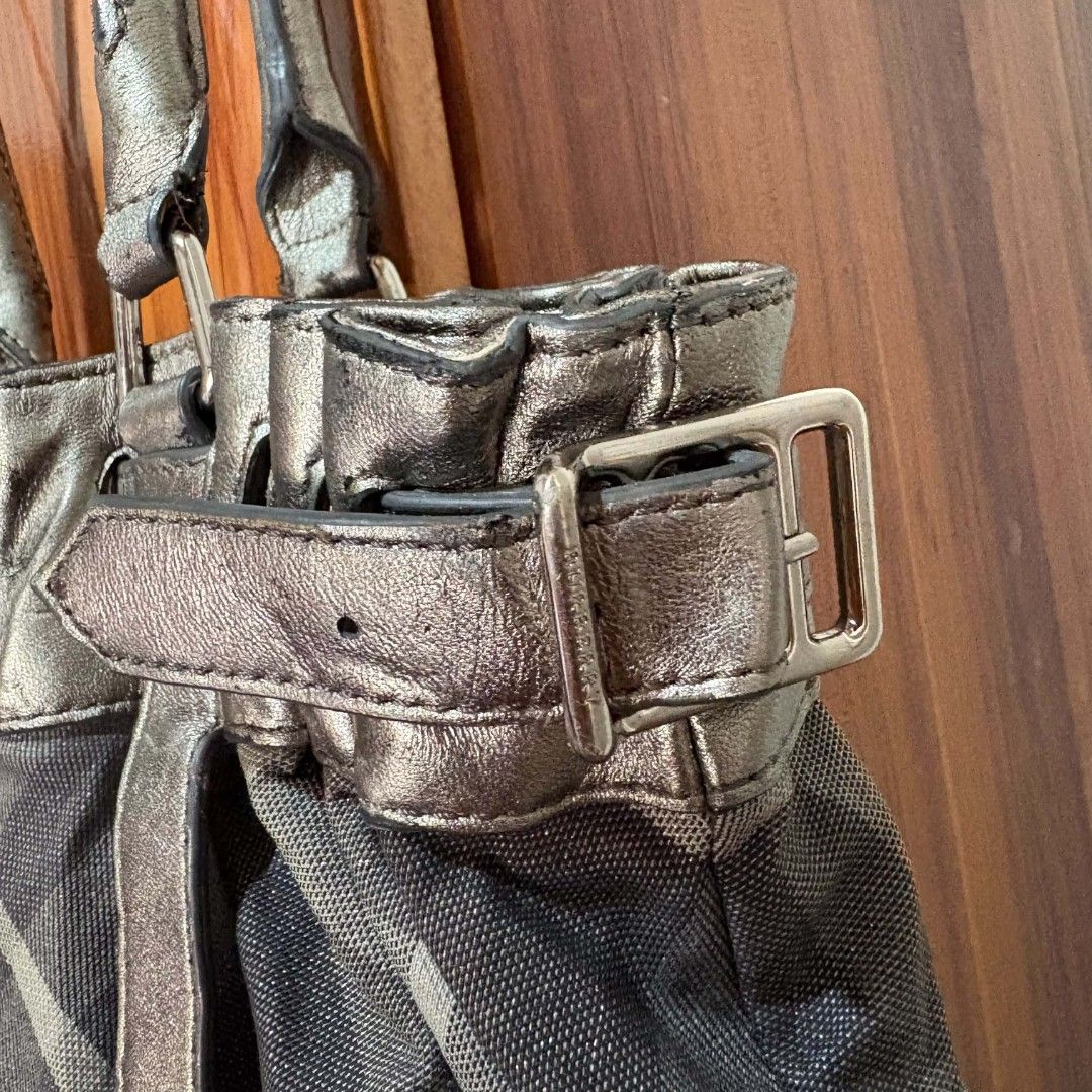 Burberry Check Tote Handbag Metallic Grey (Category: Luxury Bags & Wallets) located in Carmen. Submitted by ar_thrift00 (Listing ID 1469195820, Image 3). Description: - Brand: Burberry - Material: Metallic grey leather & signature check canvas - Design: Double shoulder straps with metal ring charm, side buckle straps for shape adjustment - Interior: Spacious, perfect for daily essentials - Condition: Leather bottom shows scuffs, stains, and wear 