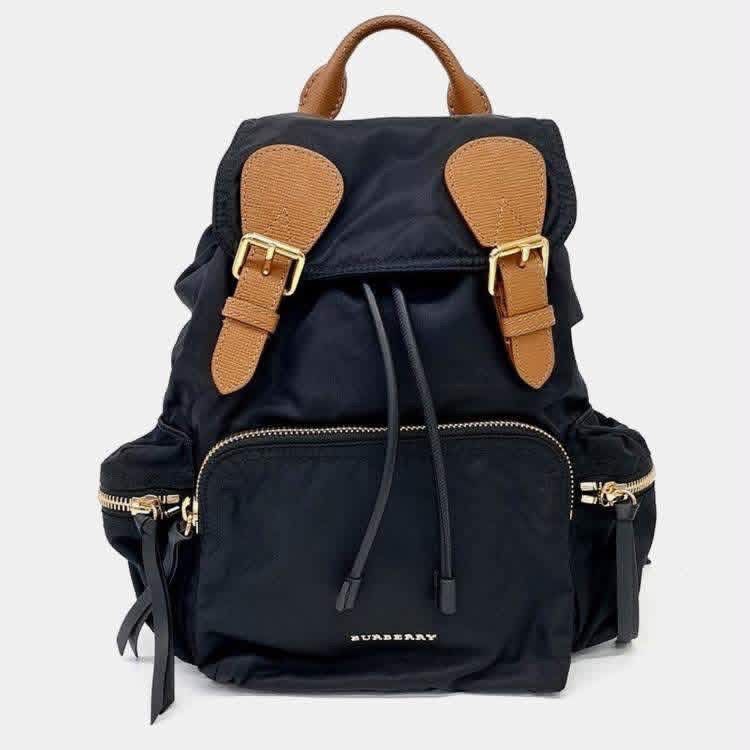 Burberry Nylon & Leather Rucksack (Category: Backpacks) located in Santiago. Submitted by evrythngulove (Listing ID 1469335430, Image 1). Description: Authentic black nylon Burberry backpack featuring chic tan leather trim and gold hardware. Includes a drawstring main compartment, multiple outer zip pockets, and comfortable adjustable straps. Perfect for everyday luxury!.