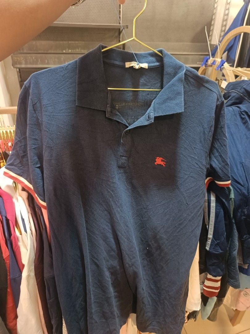 Burberry Polo Shirt (Category: Tshirts & Polo Shirts ) located in Tukuran. Submitted by coyythrift (Listing ID 1469273605, Image 2). Description: - Brand: Burberry Brit - Item: Blue Polo Shirt - Condition: Brand new with tags (BNWT) - Size: L - Material: 96% Cotton, 4% Elastane (Made in Vietnam) - Details: Red embroidered equestrian knight logo, classic collar, single-button placket, striped sleeve cuffs - Authentic and ready to ship!.