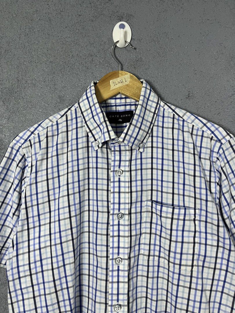 Café Soho Plaid Short Sleeve Button-Down Shirt (Category: Shirts) located in Famy. Submitted by basicthrifted (Listing ID 1469235412, Image 2). Description: - Brand: Café Soho - Style: Short-sleeve button-down shirt with collar and single chest pocket - Pattern: Classic plaid in blue, white, and black - Size: Tagged L (Actual measurements on hanger tape: 26" length x 22" width) - Material: Lightweight fabric - Condition: Clean, excellent overall 