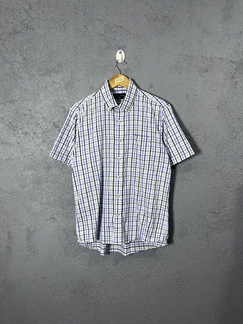 Café Soho Plaid Short Sleeve Button-Down Shirt (Category: Shirts) located in Famy. Submitted by basicthrifted (Listing ID 1469235412, Image 1). Description: - Brand: Café Soho - Style: Short-sleeve button-down shirt with collar and single chest pocket - Pattern: Classic plaid in blue, white, and black - Size: Tagged L (Actual measurements on hanger tape: 26" length x 22" width) - Material: Lightweight fabric - Condition: Clean, excellent overall 