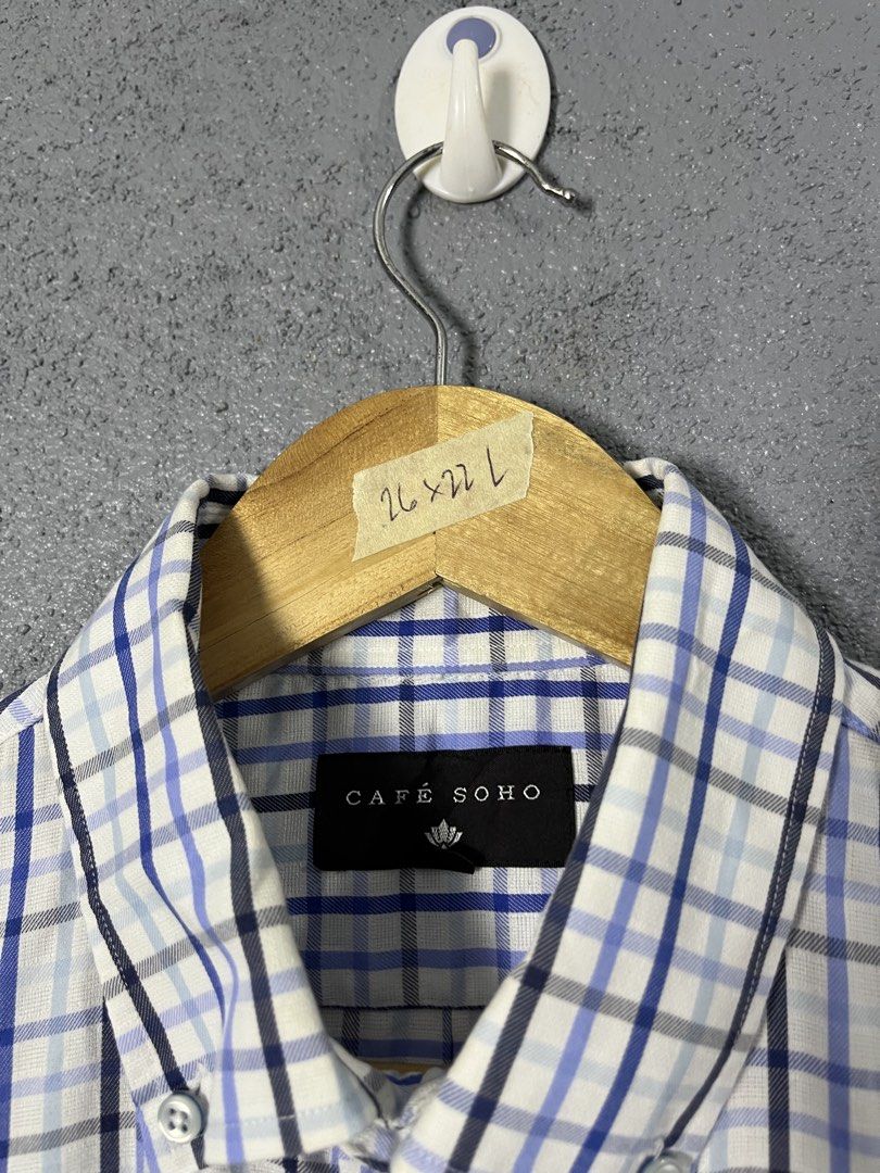 Café Soho Plaid Short Sleeve Button-Down Shirt (Category: Shirts) located in Famy. Submitted by basicthrifted (Listing ID 1469235412, Image 3). Description: - Brand: Café Soho - Style: Short-sleeve button-down shirt with collar and single chest pocket - Pattern: Classic plaid in blue, white, and black - Size: Tagged L (Actual measurements on hanger tape: 26" length x 22" width) - Material: Lightweight fabric - Condition: Clean, excellent overall 