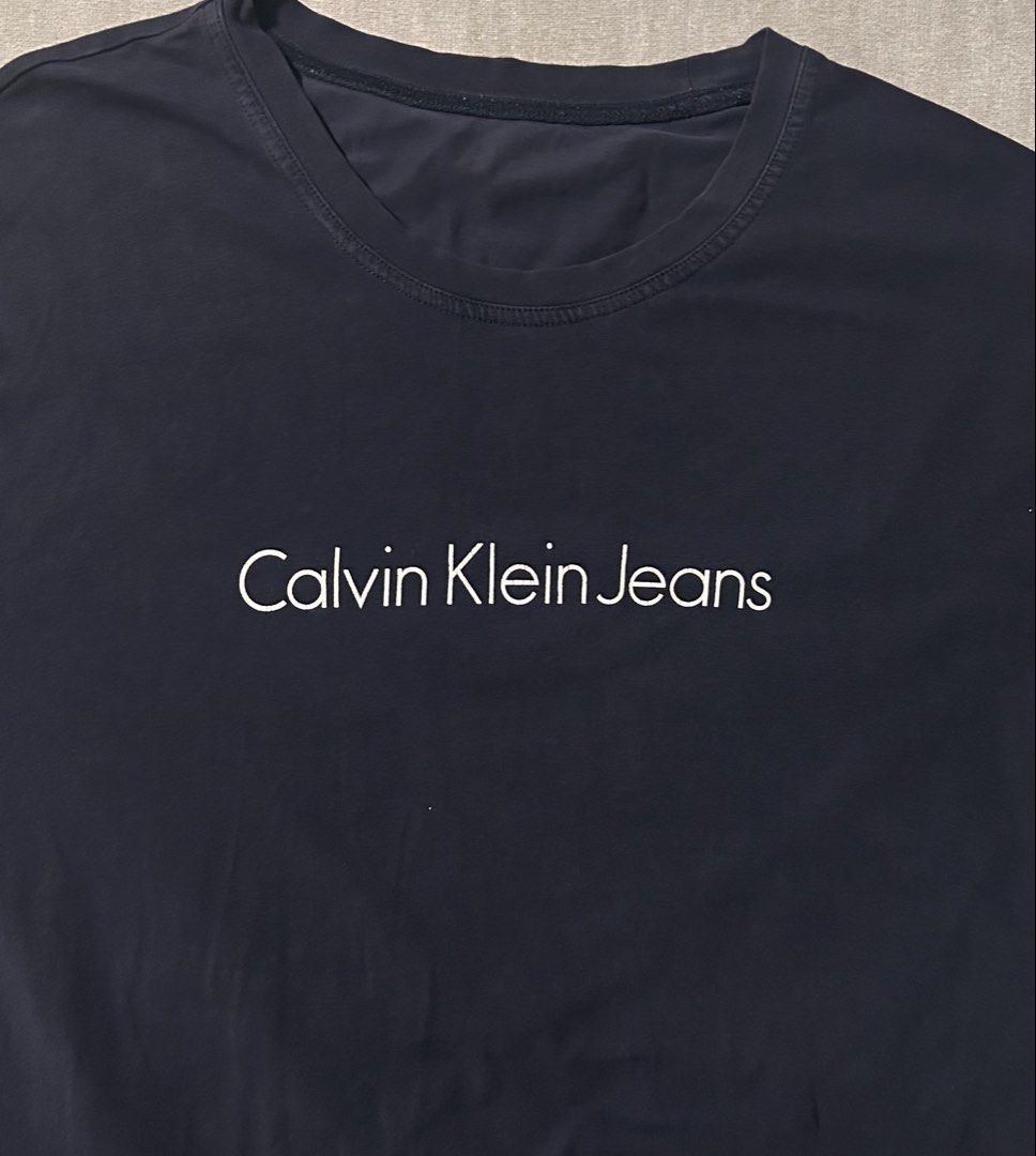 CALVIN KLEIN (Category: Tshirts & Polo Shirts ) located in Davao. Submitted by sart0ria85 (Listing ID 1469313574, Image 3). Description: Navy Blue with White logo on a Soft cotton jersey. Label details are vague. XLARGE. Size 10 GOOD CONDITION (84/100).