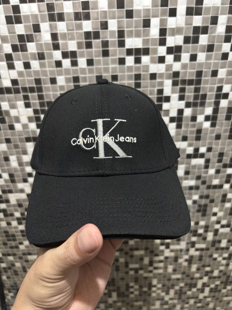 Calvin Klein Jeans Black Baseball Cap (Category: Caps & Hats) located in General Trias. Submitted by nomeeer (Listing ID 1469164140, Image 1). Description: - Brand: Calvin Klein Jeans - Color: Classic Black - Style: Curved brim baseball cap - Branding: Embroidered logo on front and repeated text on interior taped seams - Fit: Adjustable back strap with branded metal buckle - Condition: Clean, excellent pre-owned condition.