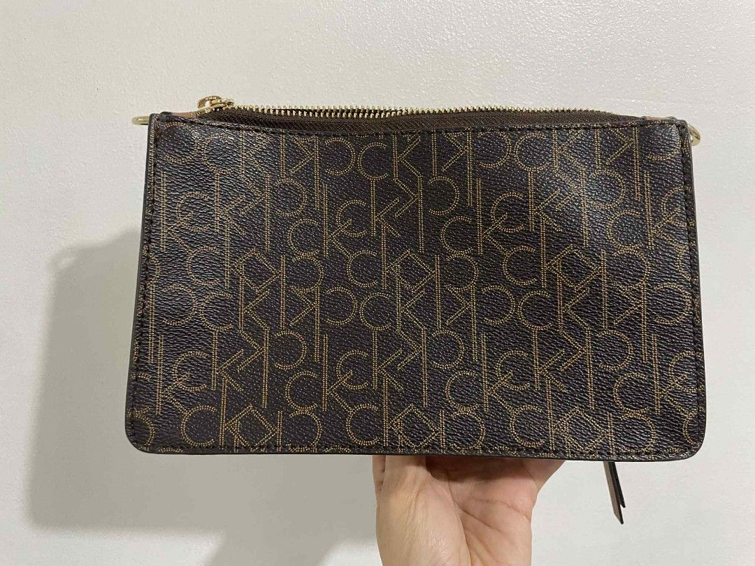 Calvin Klein Monogram Brown Crossbody Bag (Category: Cross-body Bags) located in San Pedro. Submitted by alessandrachic (Listing ID 1469313263, Image 3). Description: - Brand: Calvin Klein - Color: Dark brown with all-over monogram pattern - Hardware: Gold-tone - Strap: Matching brown, adjustable - Pockets: Front zipper pocket with CK lettering, interior slip pocket - Interior: Signature CK logo fabric lining - Condition: Clean, zippers work smoo