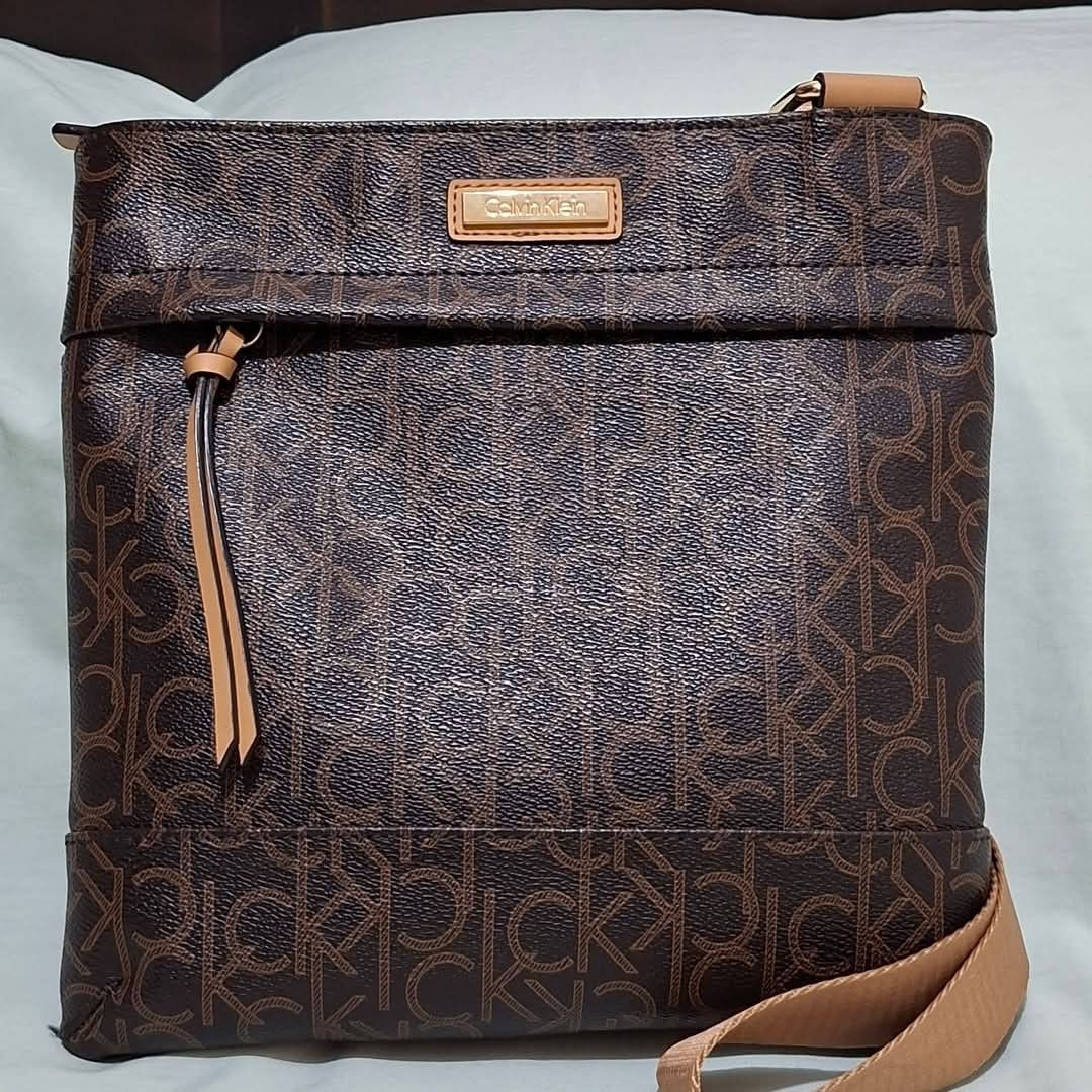 Calvin Klein Monogram Crossbody Bag Brown (Category: Cross-body Bags) located in Manila. Submitted by closetprincess (Listing ID 1469244853, Image 1). Description: - Brand: Calvin Klein - Color: Brown monogram print with tan accents - Hardware: Gold-tone brand plaque and zipper pulls - Closure: Top zip closure - Pockets: Front zipper pocket and interior magnetic snap pocket - Strap: Adjustable tan canvas shoulder strap - Interior: Lined with sign