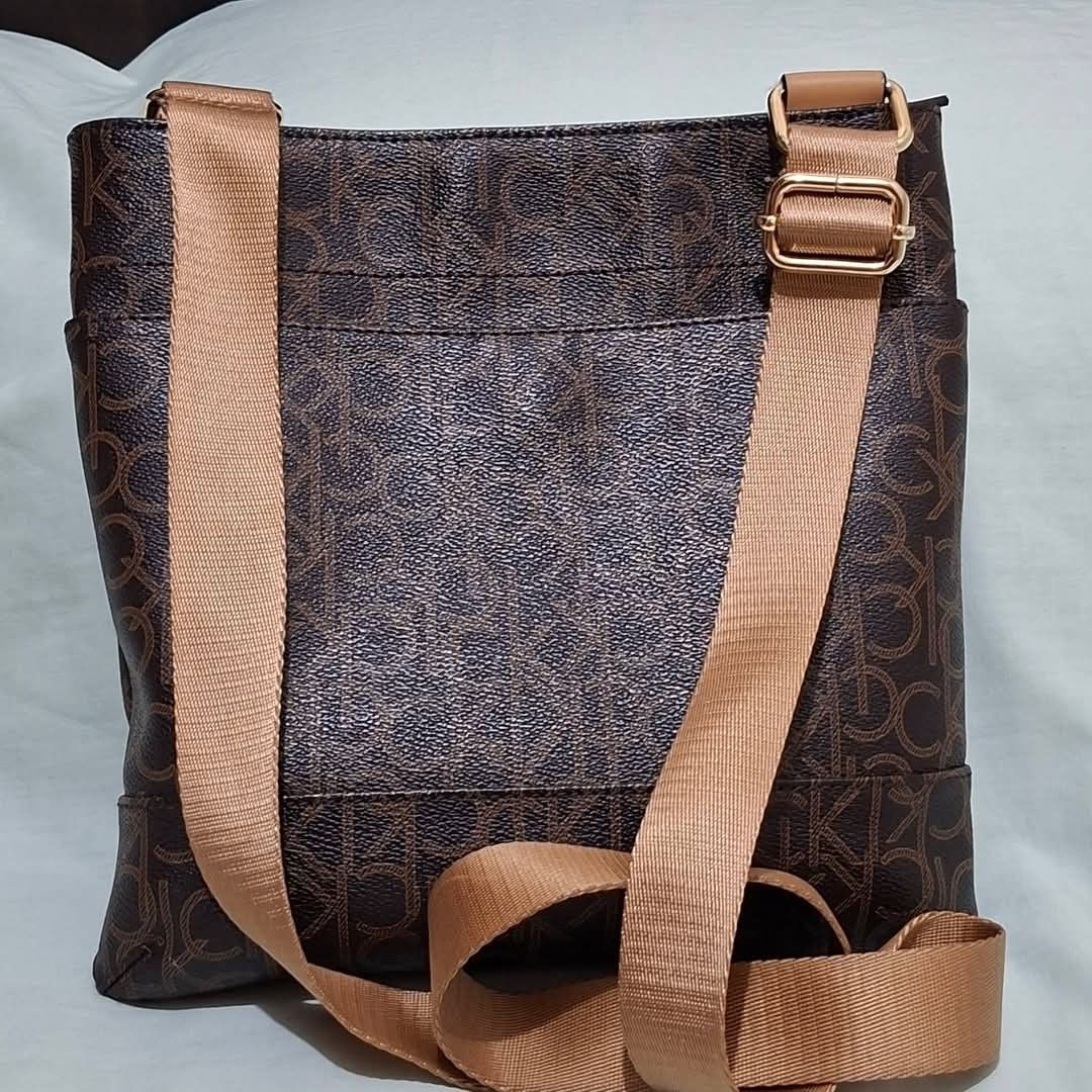 Calvin Klein Monogram Crossbody Bag Brown (Category: Cross-body Bags) located in Manila. Submitted by closetprincess (Listing ID 1469244853, Image 3). Description: - Brand: Calvin Klein - Color: Brown monogram print with tan accents - Hardware: Gold-tone brand plaque and zipper pulls - Closure: Top zip closure - Pockets: Front zipper pocket and interior magnetic snap pocket - Strap: Adjustable tan canvas shoulder strap - Interior: Lined with sign