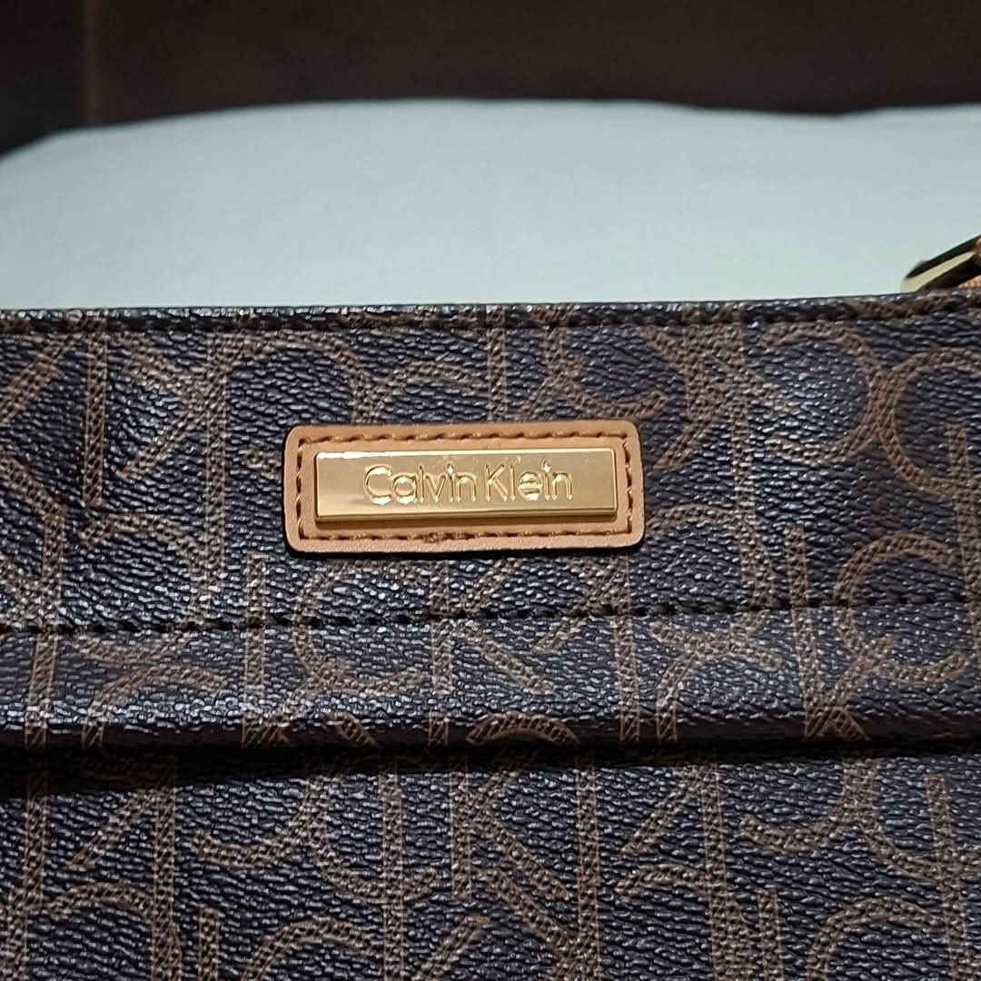 Calvin Klein Monogram Crossbody Bag Brown (Category: Cross-body Bags) located in Manila. Submitted by closetprincess (Listing ID 1469244853, Image 2). Description: - Brand: Calvin Klein - Color: Brown monogram print with tan accents - Hardware: Gold-tone brand plaque and zipper pulls - Closure: Top zip closure - Pockets: Front zipper pocket and interior magnetic snap pocket - Strap: Adjustable tan canvas shoulder strap - Interior: Lined with sign