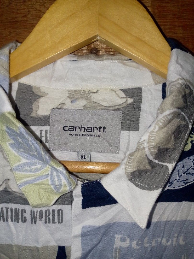 Carhartt Short Sleeve Patchwork Floral Button Up Shirt (Category: Tshirts & Polo Shirts ) located in Digos. Submitted by natnateliv39056 (Listing ID 1469185255, Image 2). Description: - Brand: Carhartt - Style: Short sleeve button-up shirt - Design: White multi-color patchwork floral pattern with subtle Carhartt text accents - Features: Collared neckline, front button closure, double lower front pockets - Fit: Relaxed fit, perfect for warm weathe
