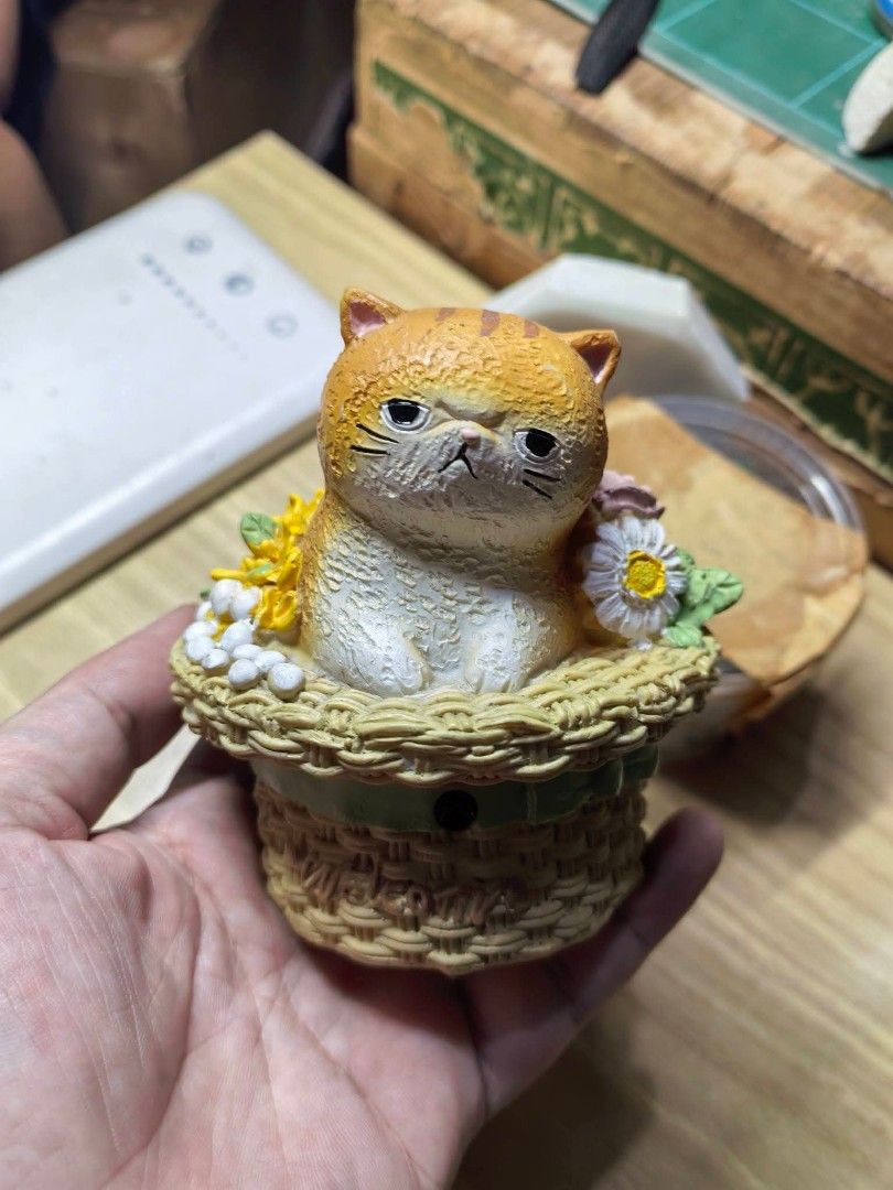 Cat in Flower Basket Welcome Figurine (Category: Other Home Decor) located in Cebu City. Submitted by dudes_villanueva (Listing ID 1469281648, Image 2). Description: Cat in Flower Basket Welcome Figurine / Sound Box Hand-painted novelty decor featuring an adorable grumpy orange tabby cat nestled inside a woven flower basket decorated with roses and daisies. ​Features a "Welcome" script on the front, an electronic sensor/audio module port, and a b