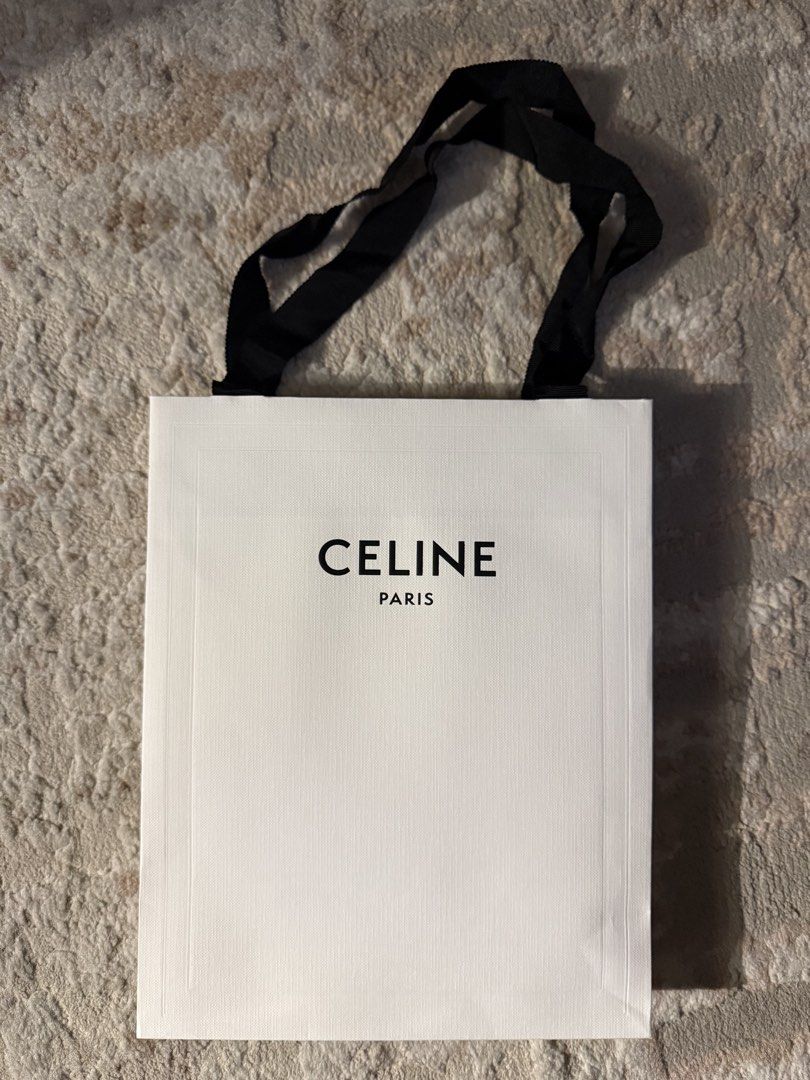 Celine Paris White Paper Shopping Bag (Category: Luxury Bags & Wallets) located in Manila. Submitted by hotdealsph (Listing ID 1469312029, Image 1). Description: - Authentic Celine Paris paper shopping bag - Color: White with bold black central branding - Material: Textured heavy paper stock - Handles: Premium black grosgrain ribbon - Design: Clean rectangular profile with folded sides - Ideal for gifting.
