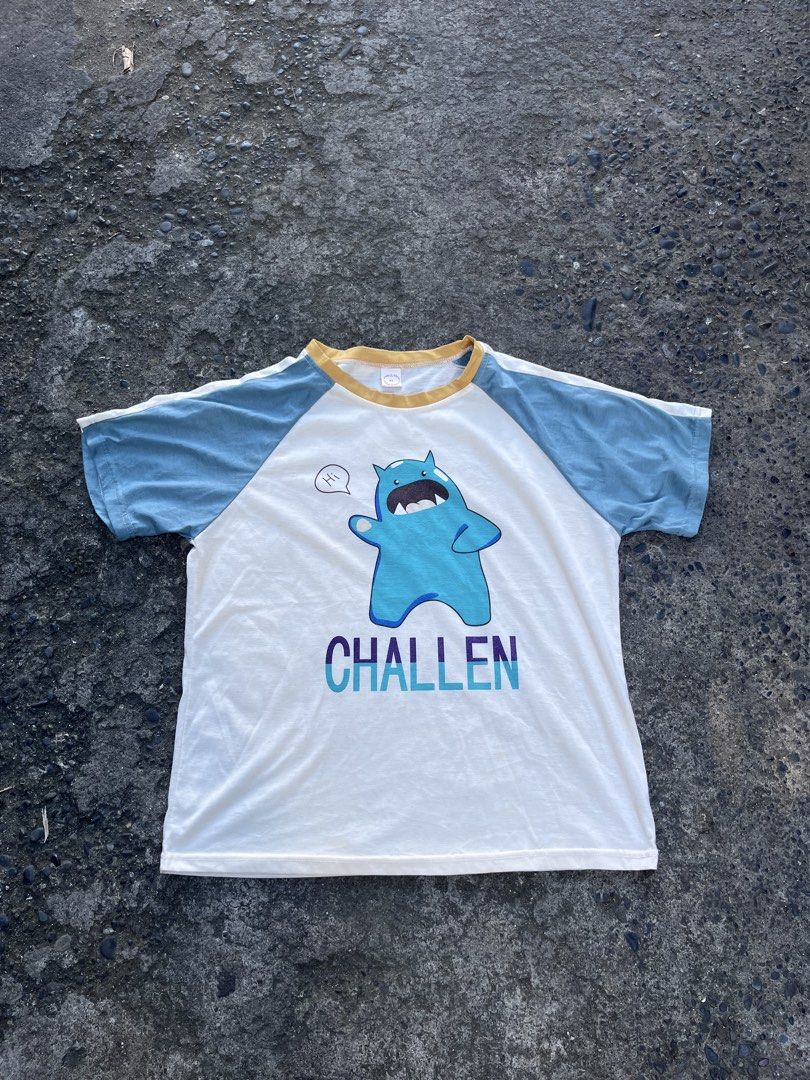 Challen Blue Monster Raglan T-Shirt (Category: Tshirts & Polo Shirts ) located in Manila. Submitted by coybns (Listing ID 1469188370, Image 1). Description: - Style: Casual raglan t-shirt with light blue sleeves and yellow collar trim - Design: Blue cartoon monster waving with a "" speech bubble and bold "challen" text in blue and purple - Material: Soft, breathable everyday cotton - Fit: Comfortable regular fit, perfect for daily wear - Conditio