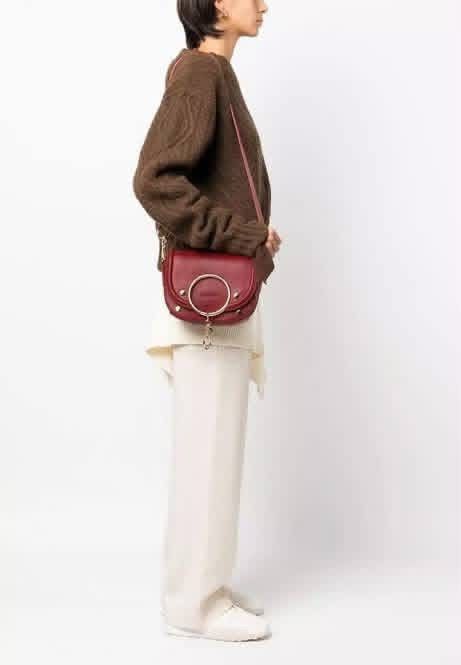 Chloe Crossbody Bag Burgundy (Category: Cross-body Bags) located in Santiago. Submitted by evrythngulove (Listing ID 1469335874, Image 1). Description: Burgundy suede and leather crossbody bag from See By Chloe. Iconic oversized round ring detail on the front flap with gold-tone hardware. Magnetic closure. Adjustable shoulder strap. Black fabric lined interior with a slip pocket and debossed leather brand patch. Rich wine red colorway. Compact ev