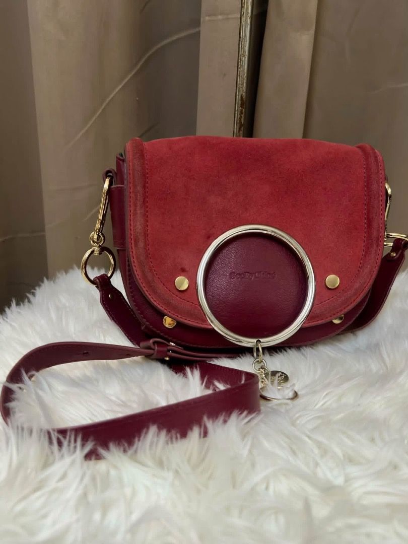 Chloe Crossbody Bag Burgundy (Category: Cross-body Bags) located in Santiago. Submitted by evrythngulove (Listing ID 1469335874, Image 2). Description: Burgundy suede and leather crossbody bag from See By Chloe. Iconic oversized round ring detail on the front flap with gold-tone hardware. Magnetic closure. Adjustable shoulder strap. Black fabric lined interior with a slip pocket and debossed leather brand patch. Rich wine red colorway. Compact ev