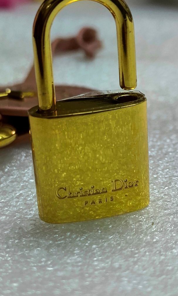 Christian Dior Bag tag with Lock & Key (Category: Luxury Accessories) located in Manila. Submitted by blings_thingies (Listing ID 1469177131, Image 2). Description: • Circular pink leather tag embossed with gold-lettered "Christian Dior" and "Paris", centered with a raised gold-finish star emblem and a matching hanging key. • Accessories: A matching gold-finish padlock featuring the engraved Dior signature..