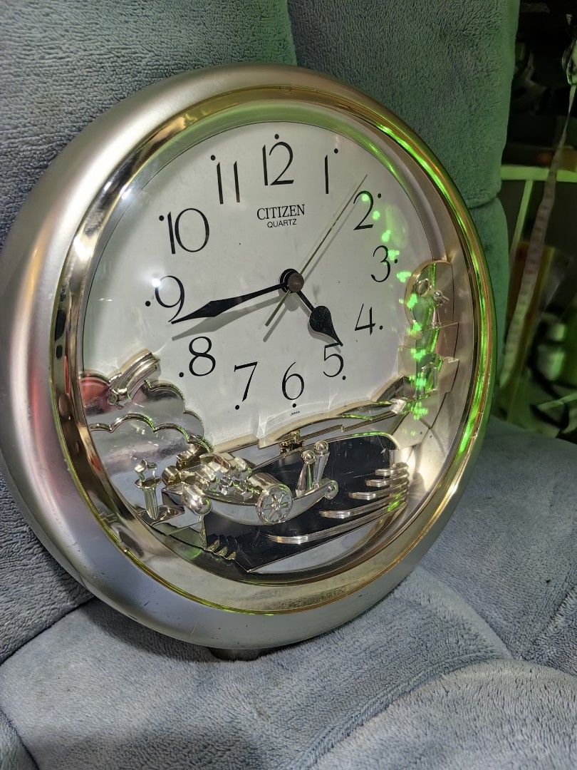 Citizen Quartz Round Wall Clock with Moving Gear Design (Category: Clocks) located in Rizal. Submitted by gkstcenit (Listing ID 1469169899, Image 2). Description: Round wall clock made by Citizen Quartz. Silver and gold tone frame with white clock face and black Arabic numerals. Lower section has an intricate moving gear mechanism with metallic sculptural elements including staircases and clouds. Diameter measures roughly 28 centimeters based on 