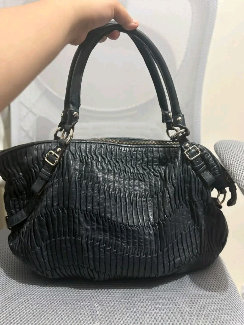 Coach Ruffle Leather Handbag Black (Category: Luxury Bags & Wallets) located in Alfonso. Submitted by y2kbuyandsell (Listing ID 1469204267, Image 2). Description: - Brand: Coach - Material: Genuine leather in classic black - Design: Elegant gathered detailing with silver-tone hardware and side buckle accents - Closure & Handles: Secure zippered top closure with dual top handles - Interior: Spacious light blue lining with the official Coach creed 