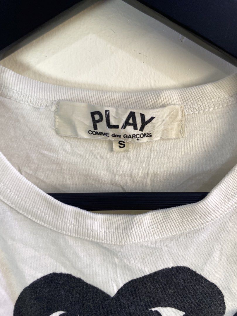 COMME des GARÇONS Play Double Heart Tee White Size S (Category: Shirts) located in Manila. Submitted by declutterpromax (Listing ID 1469220666, Image 2). Description: - Brand: Play Comme des Garçons - Size: Small - Color: White - Design: Iconic double heart graphic on chest (black heart logo with smaller heart patch) - Style: Crew neck, short sleeves - Condition: Good overall, with minor yellowing/stains near the front lower section - Authenticit