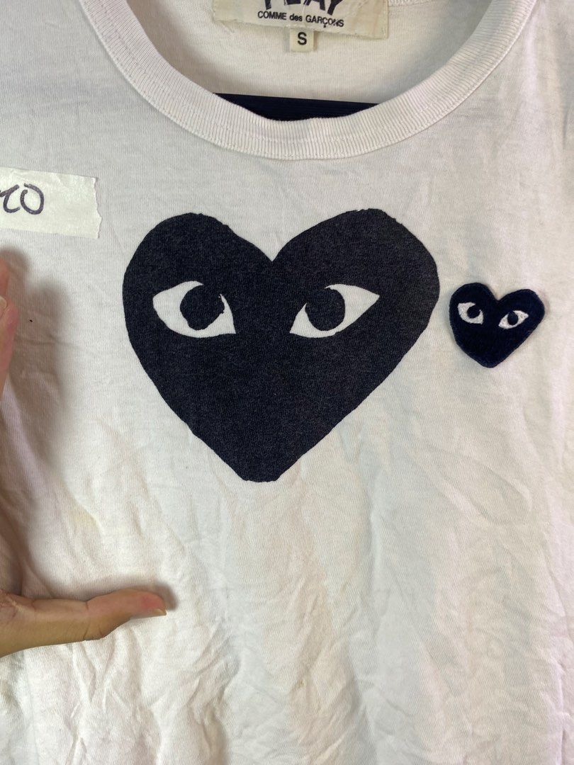 COMME des GARÇONS Play Double Heart Tee White Size S (Category: Shirts) located in Manila. Submitted by declutterpromax (Listing ID 1469220666, Image 3). Description: - Brand: Play Comme des Garçons - Size: Small - Color: White - Design: Iconic double heart graphic on chest (black heart logo with smaller heart patch) - Style: Crew neck, short sleeves - Condition: Good overall, with minor yellowing/stains near the front lower section - Authenticit