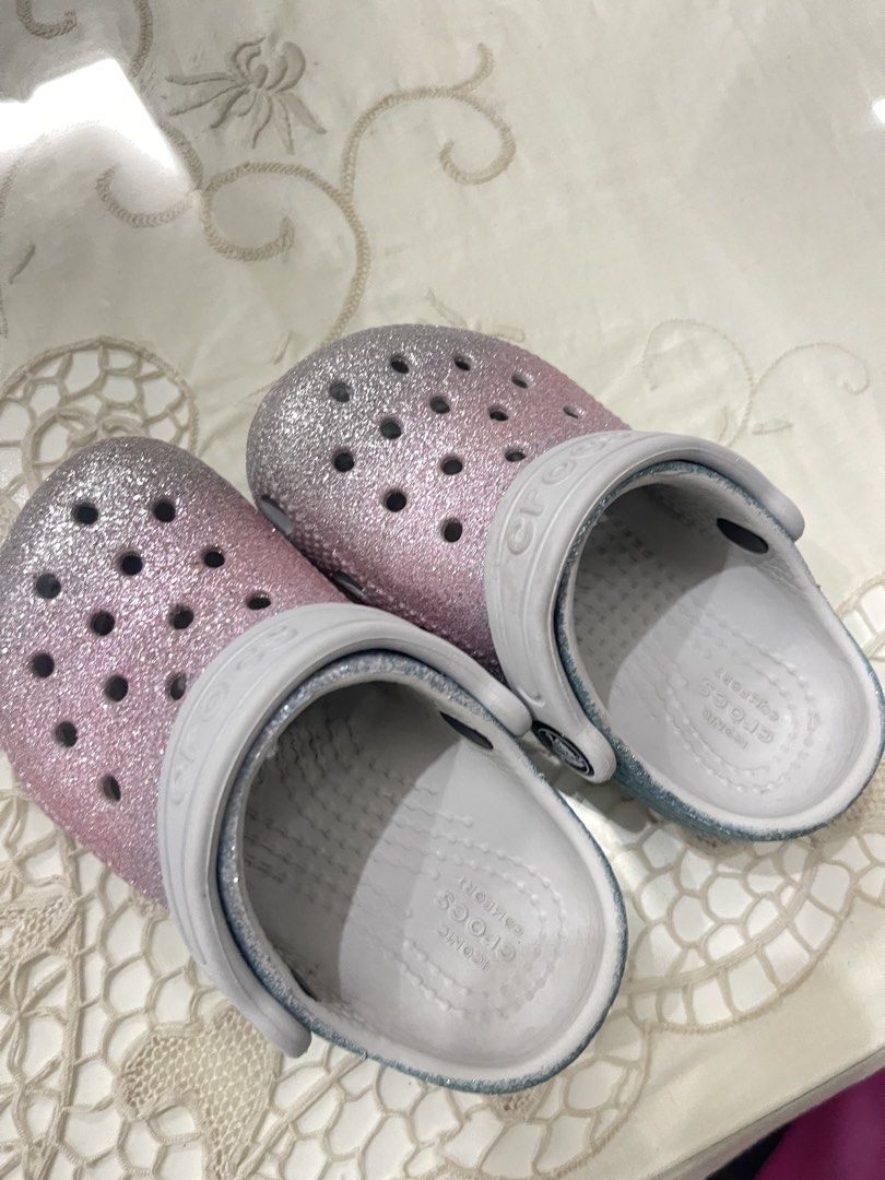 Crocs Classic Glitter Clogs Pink Blue Size C7 (Category: Slippers and slides) located in Lipa City. Submitted by kissesann (Listing ID 1469165648, Image 1). Description: - Item: Pink and blue glitter Crocs clogs with white strap - Size: C7 (molded on sole) - Features: Iconic comfort footbed, slip-on design, ventilation holes on top - Condition: Good, with light signs of wear on the soles - Perfect for daily wear and easy to clean.